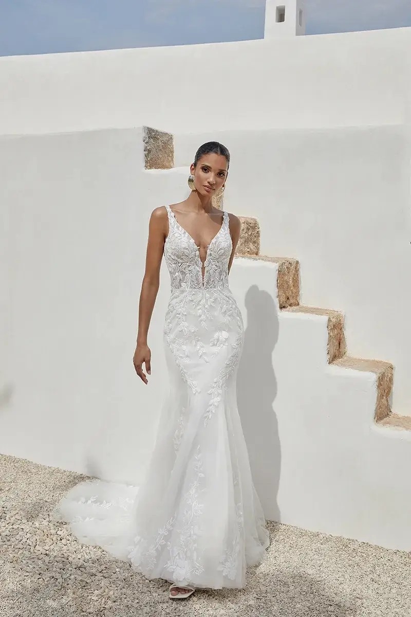 Model is wearing a fit and flare wedding dress with a plunging neckline and sheer bodice by justin alexander