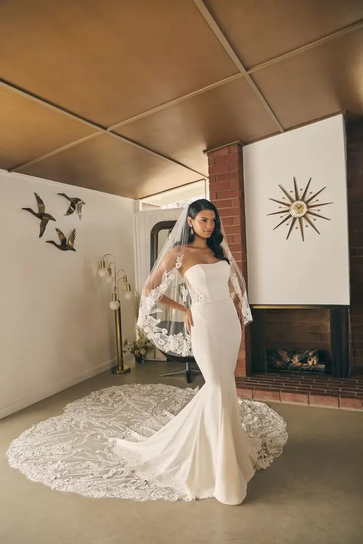 model is wearing a strapless mermaid gown with a train