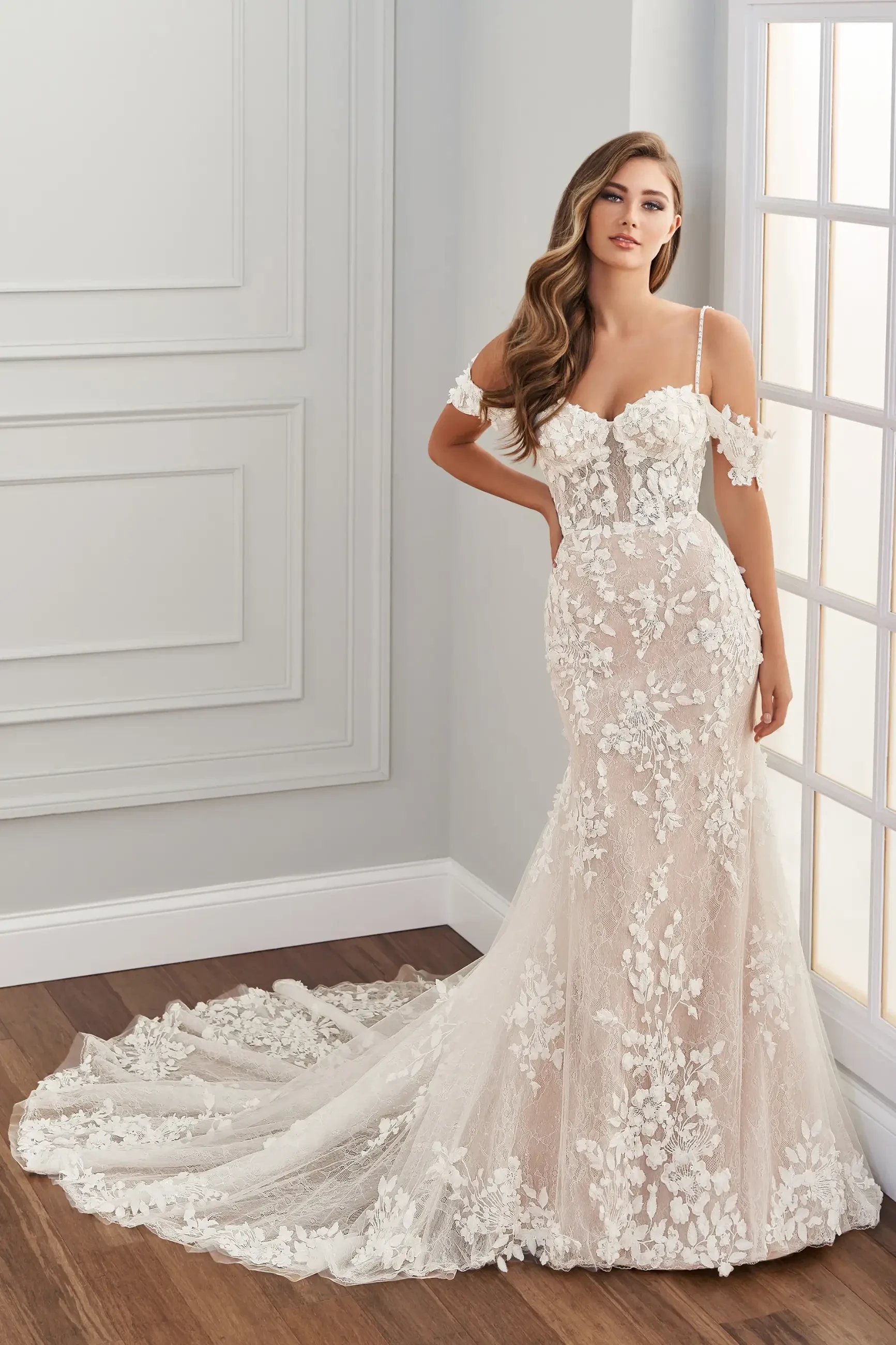 model is wearing an off the shoulder lace fit and flare bridal gown 