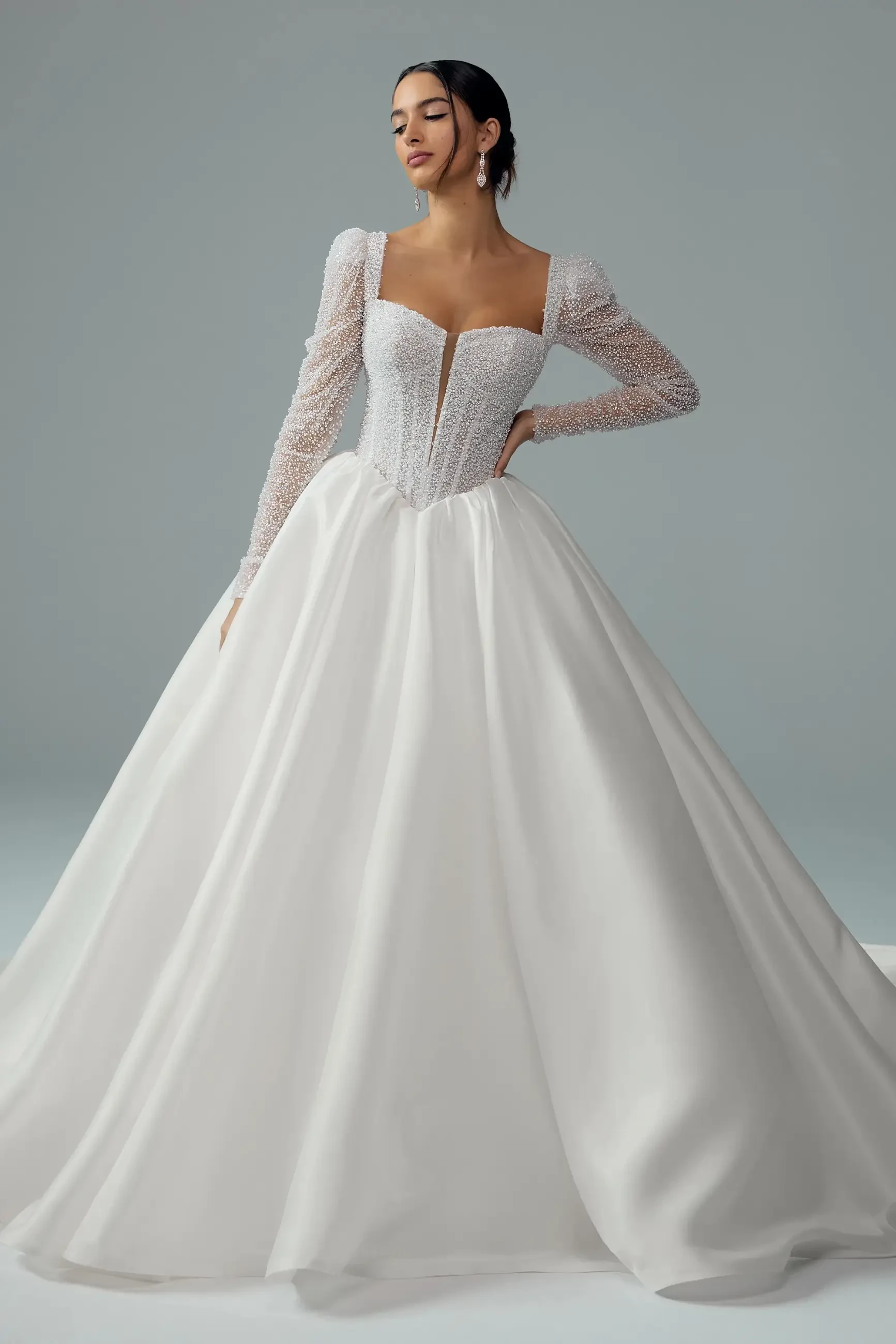 model is wearing a long sleeve ball gown wedding dress