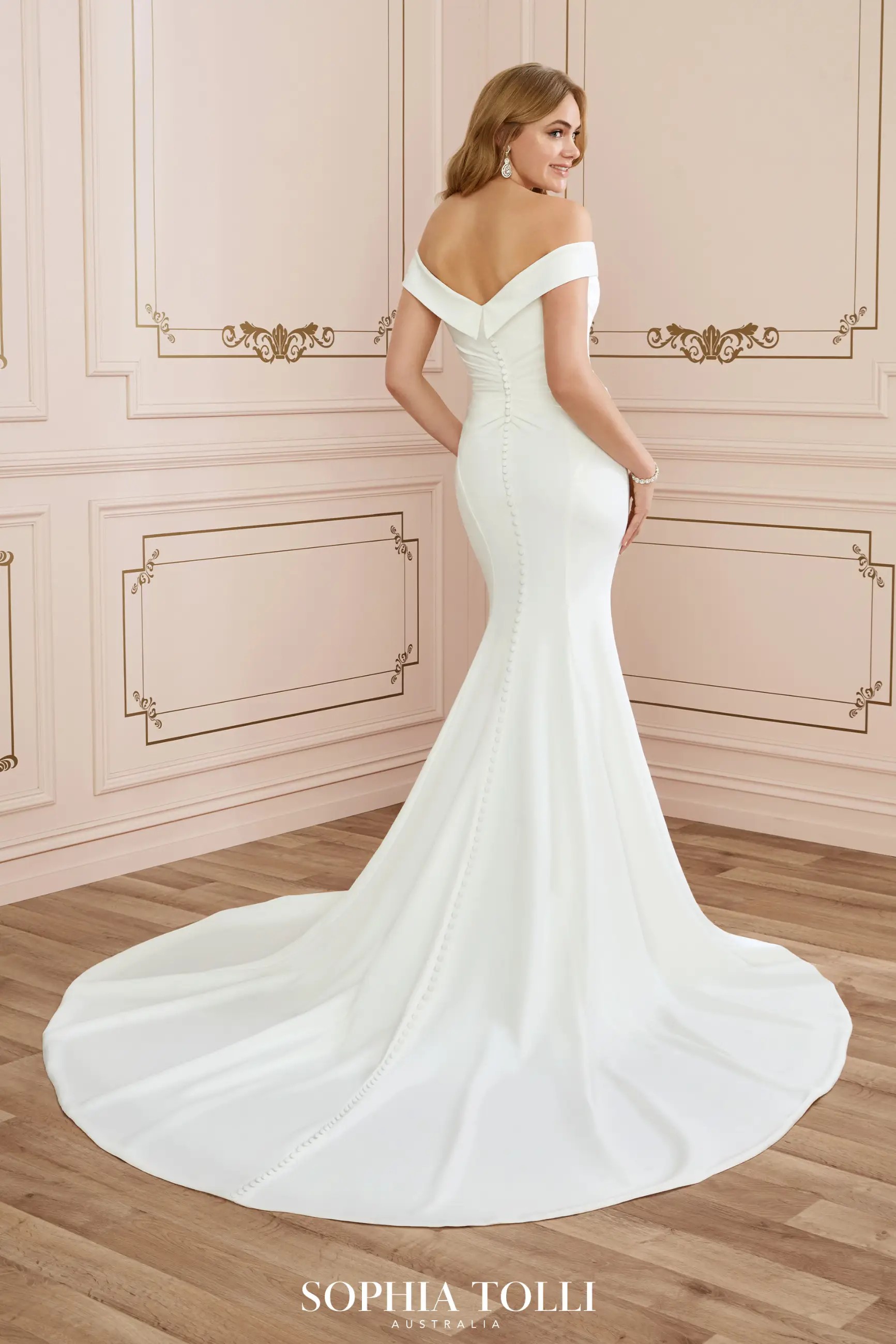 Model is wearing a sleek crepe bridal gown with off the shoulder straps by sophia tolli