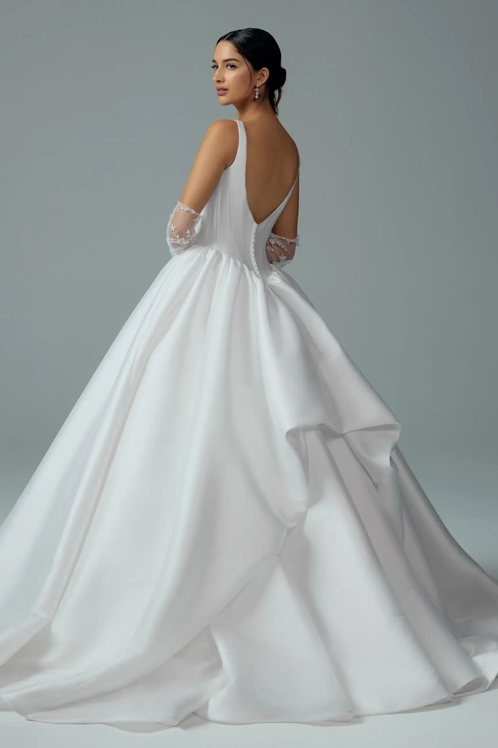 model is wearing a sleeveless ball gown wedding dress with gauntlet sleeves
